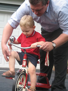 man teaching a child to ride a tricycle